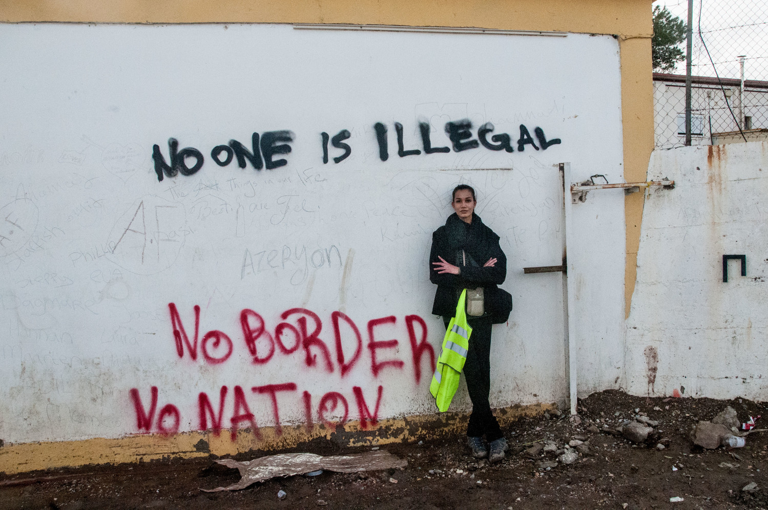Personas refugiadas que llegan a Lesvos (Grecia) desde Turquía. Una mujer se reclina sobre una pared que pone ninguna persona es ilegal.