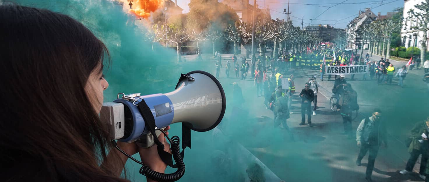 Una manifestante habla a través de un megáfono mientras el humo se eleva cerca de las personas que participan en la manifestación anual del Primero...